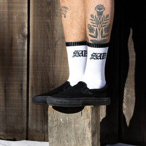 White socks with black top and toe on a wooden block sad sock
